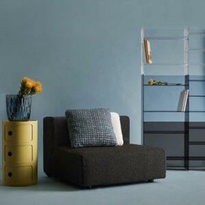 Flexibles Dekorations-Objekt mit Stauraum: Der Kartell Componibili macht sich in seiner erdigen Farbe gut neben dem schwarzen Sessel und vor der blaugrauen Wand.