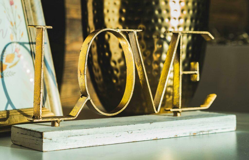 Ein goldener LOVE-Schriftzug macht sich gut auf einem Sideboard. Vor allem bei einem Valentinstag Dinner zu Hause.